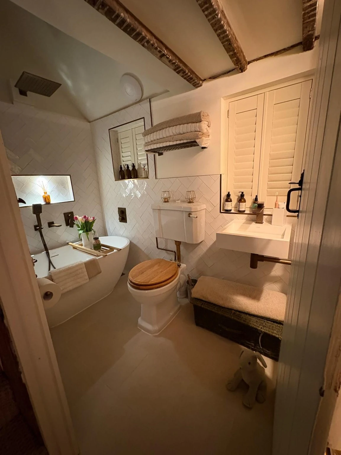 Finished compact bathroom with a larger bath, wall-mounted basin, toilet and shuttered windows