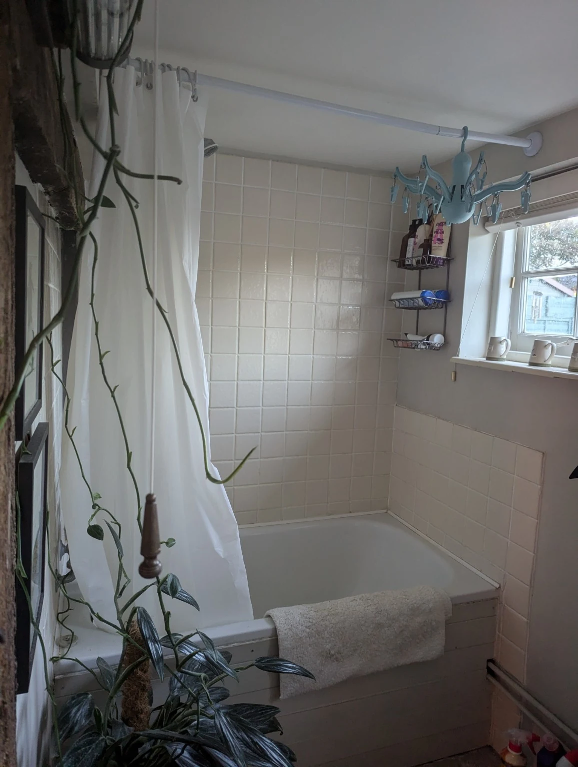 Original bathroom showing the low ceiling, shower curtain rail and bath beside the window