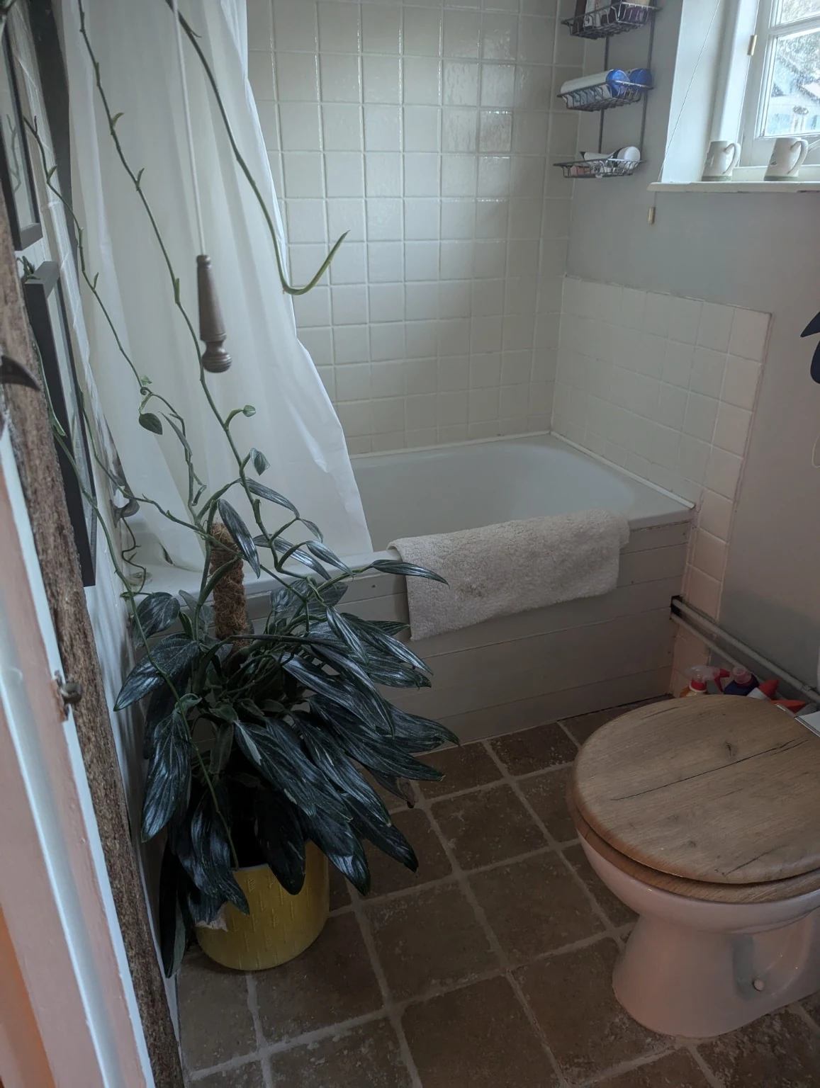 Original small bathroom with a panelled bath, shower curtain, toilet and tiled floor