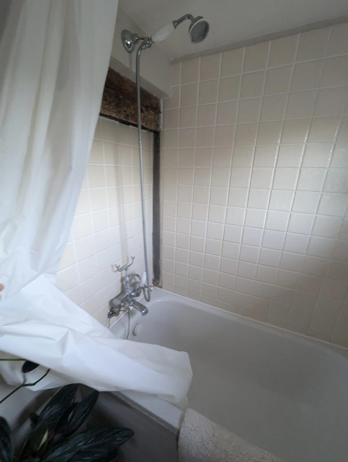 Original bath and shower fittings beneath the low bathroom ceiling