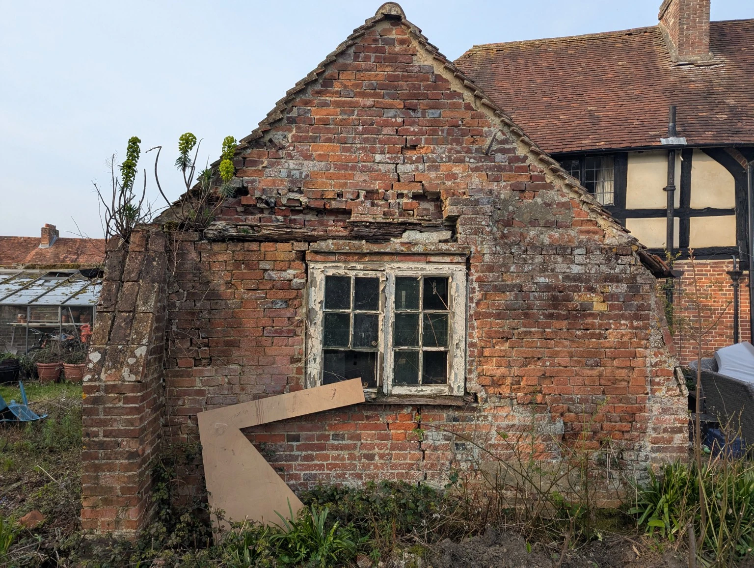 Before restoration: the weathered brick gable with cracked masonry, a timber lintel and an old window