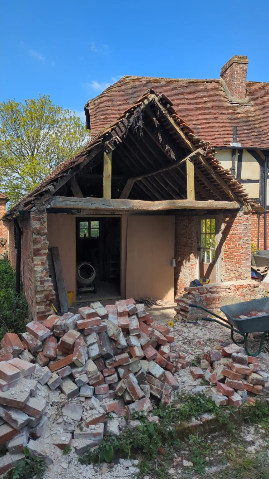 Front view at the end of demolition, with the gable opened up and recovered bricks in the foreground