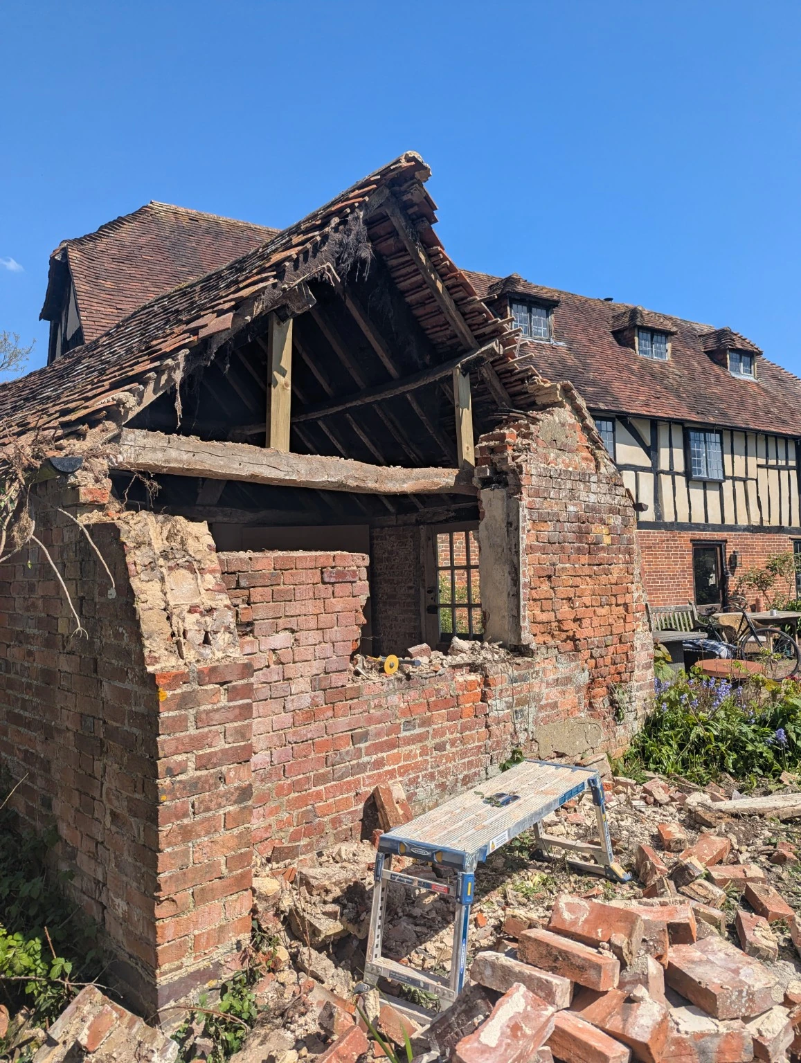 Side view at the end of demolition, showing the partly dismantled brick gable and exposed roof timbers