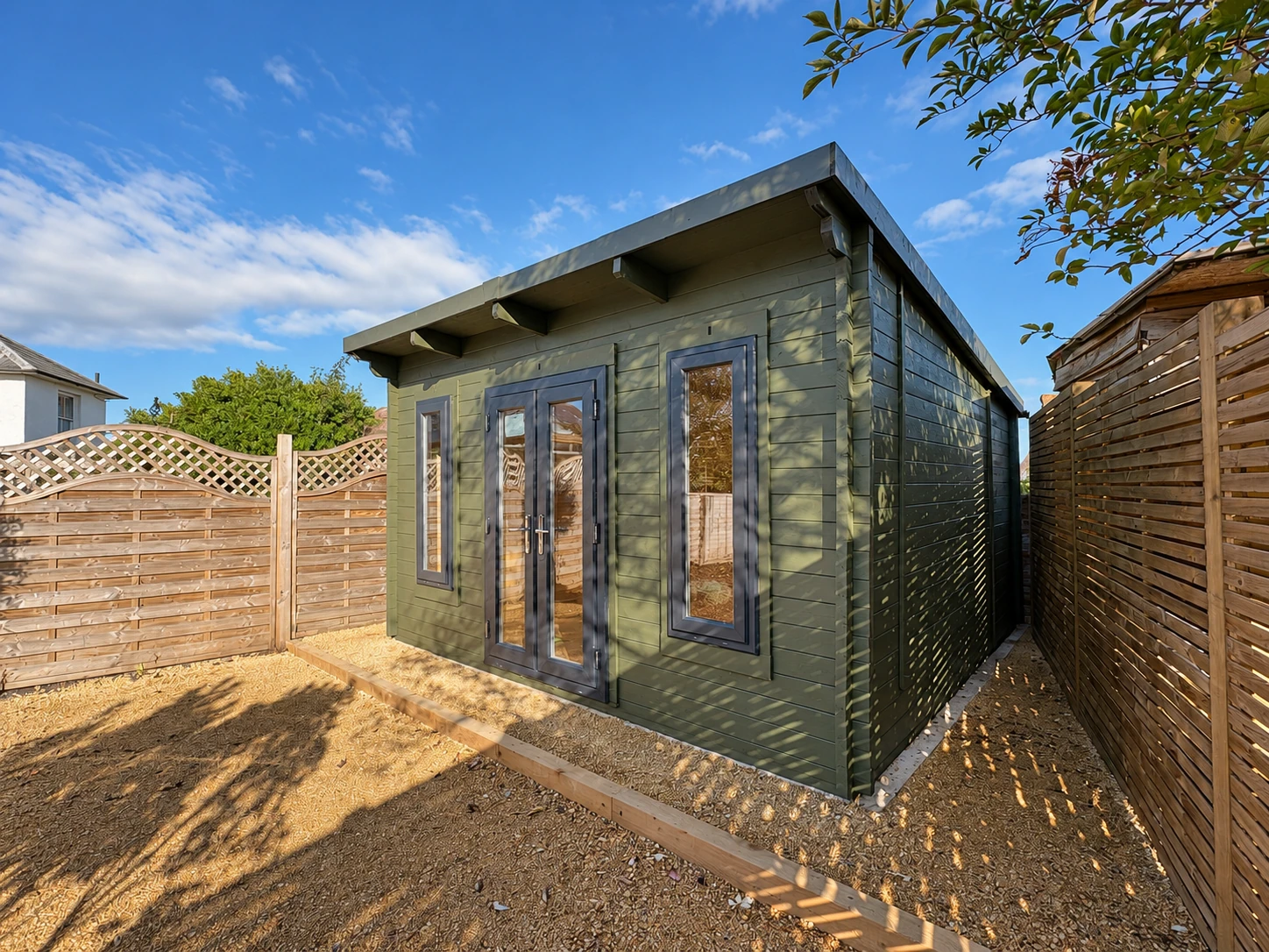 Angled view of the green timber garden room, showing the glazed front and right side