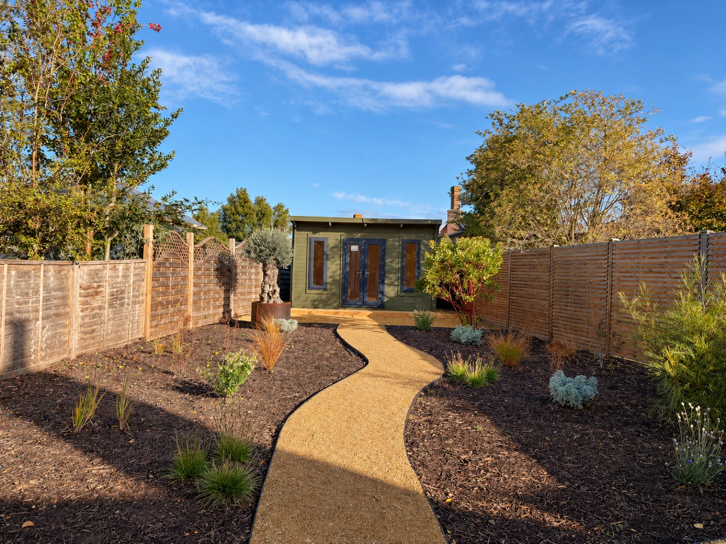 Curving gravel path through the garden leading to the timber garden room